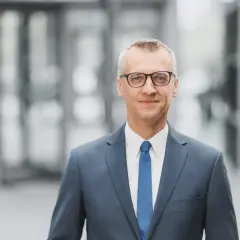 Uśmiechnięty mężczyzna w garniturze, symbolizujący wzrost gospodarczy i sukces w biznesie.