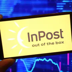 Telefon wyświetla logo InPost. W tle wykresy giełdowe, sugerujące analizę akcji InPost.