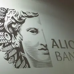 Stylizowany portret z piórami i napis ALIOR BANK. Symbolizuje stabilność i rozwój akcji Alior.