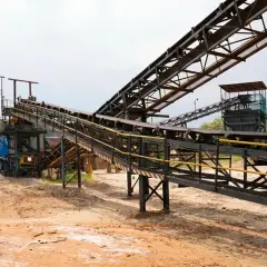 Przemysłowy krajobraz z taśmociągami, które transportują materiały. W tle widać budynki i wzgórza. To miejsce, gdzie odbywają się notowania bumech.
