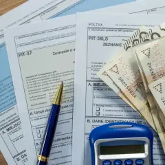 Formularze PIT, długopis, kalkulator i banknoty 200 zł. Zastanawiasz się, co można odliczyć w PIT? Sprawdź!
