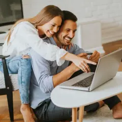 Szczęśliwa para robi zakupy online, ciesząc się ulgą na internet i lampką wina.