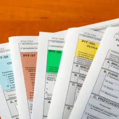Różne formularze PIT (PIT-38, PIT-37, PIT-36, PIT-36L, PIT-28) leżą na drewnianym blacie. Czy trzeba rozliczać PIT-11?