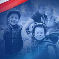 Uśmiechnięte dzieci w kaskach na rowerach, symbolizujące radość i wsparcie dla rodzin w ramach programu Polski Ład.