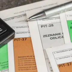 Kalkulator i długopis na dokumentach PIT. Przygotowanie do rozliczenia ulgi rehabilitacyjnej na samochód.