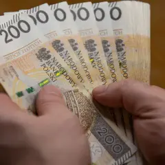 Dłonie trzymają plik banknotów po 200 zł. To może być wypłata, która wynosi 5000 brutto.
