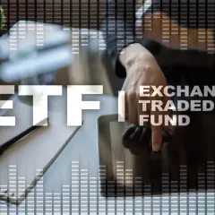 Ręka dotyka ekranu tabletu z napisem ETF (Exchange Traded Fund) na tle wykresów.