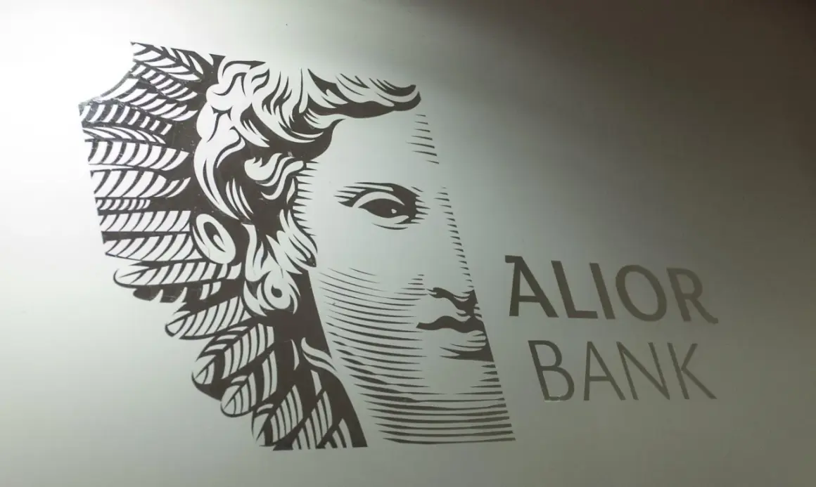 Stylizowany portret z piórami i napis ALIOR BANK. Symbolizuje stabilność i rozwój akcji Alior.