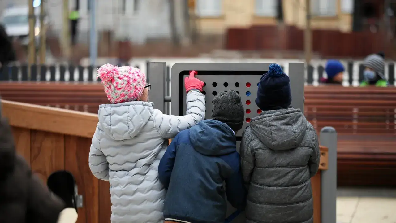 Dzieci bawią się interaktywną tablicą na placu zabaw. To idealne miejsce na wspólne chwile, prawdziwy pit 0 dla rodzin.
