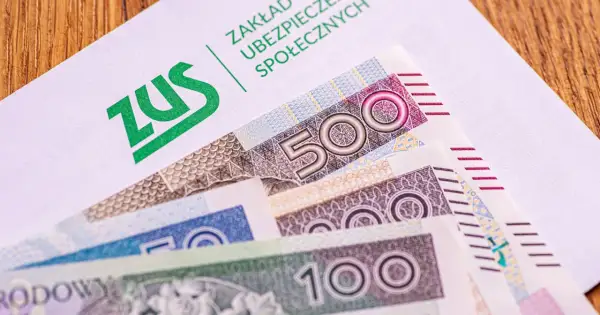ZUS na białej kopercie, pod nią polskie banknoty 500, 200 i 100 zł. Czekamy na 14. emeryturę.