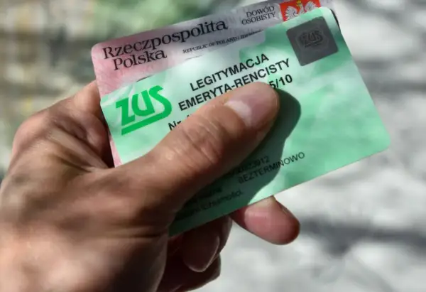 Dłoń trzyma zieloną legitymację emeryta-rencisty ZUS. Dokument potwierdza uprawnienia do świadczeń.