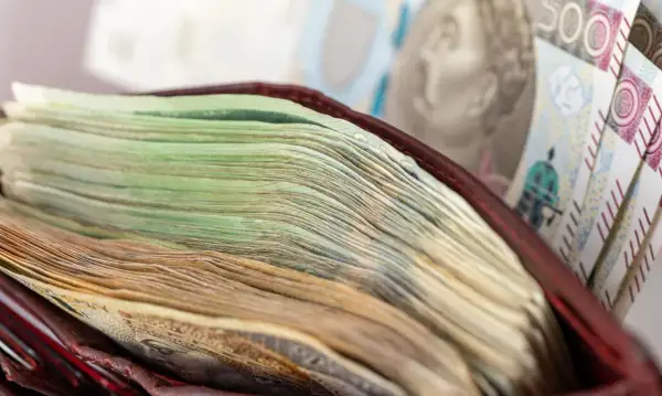 Stos banknotów w portfelu, w tle banknot 500 zł.