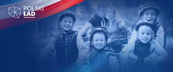 Uśmiechnięte dzieci w kaskach na rowerach, symbolizujące radość i wsparcie dla rodzin w ramach programu Polski Ład.