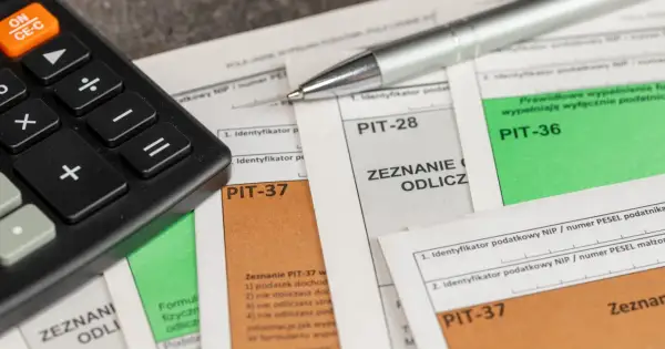 Kalkulator i długopis na dokumentach PIT. Przygotowanie do rozliczenia ulgi rehabilitacyjnej na samochód.
