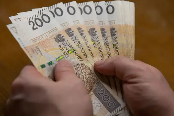 Dłonie trzymają plik banknotów po 200 zł. To może być wypłata, która wynosi 5000 brutto.
